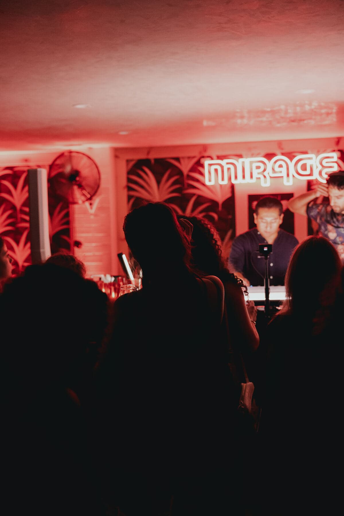 LP behind the decks under the Mirage sign, crowd silhouetted in red light