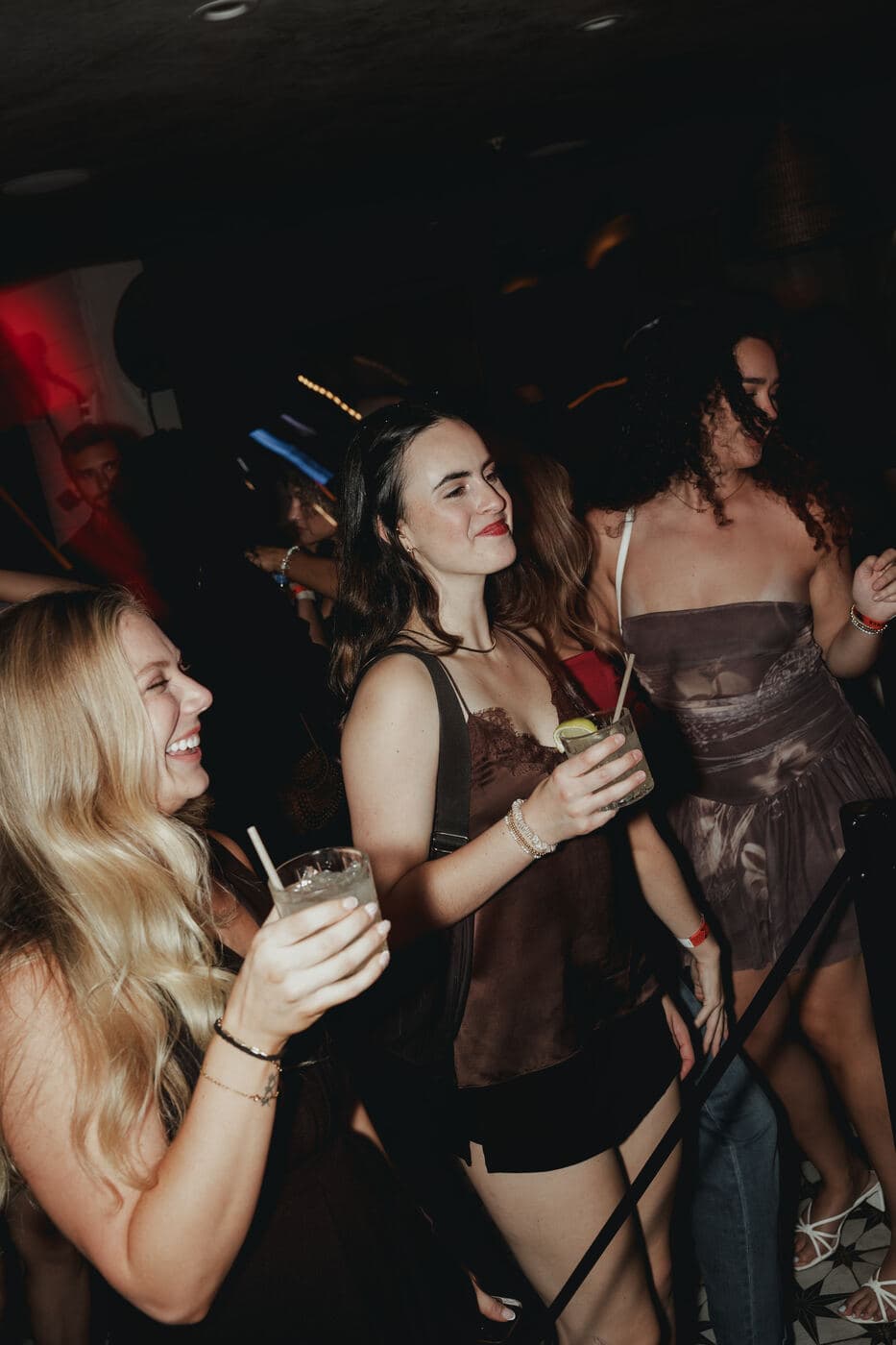Two women laughing with drinks in hand on the dance floor