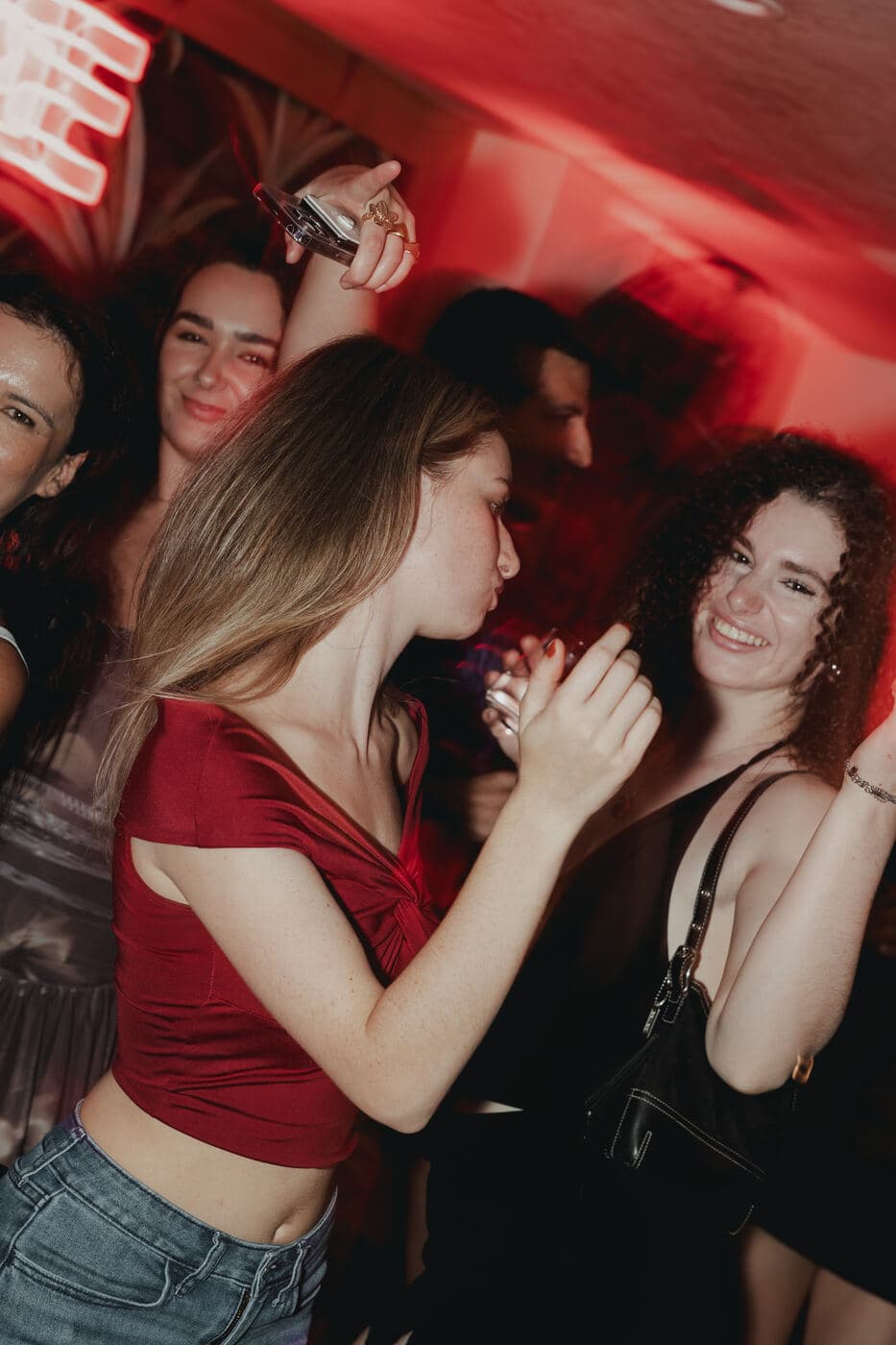 Dancers close to the camera under red club lighting