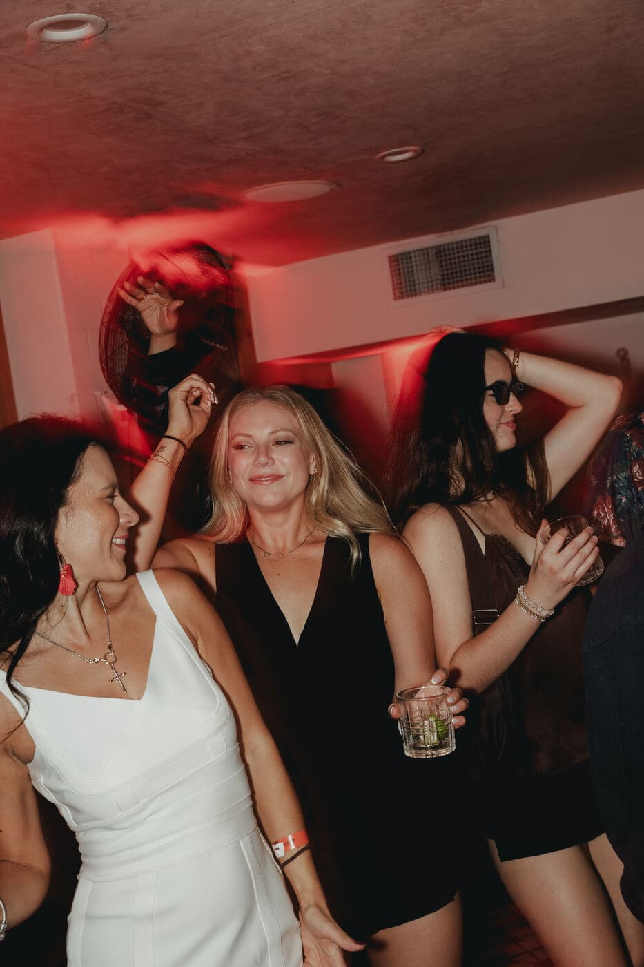 A group dancing and laughing together under red light