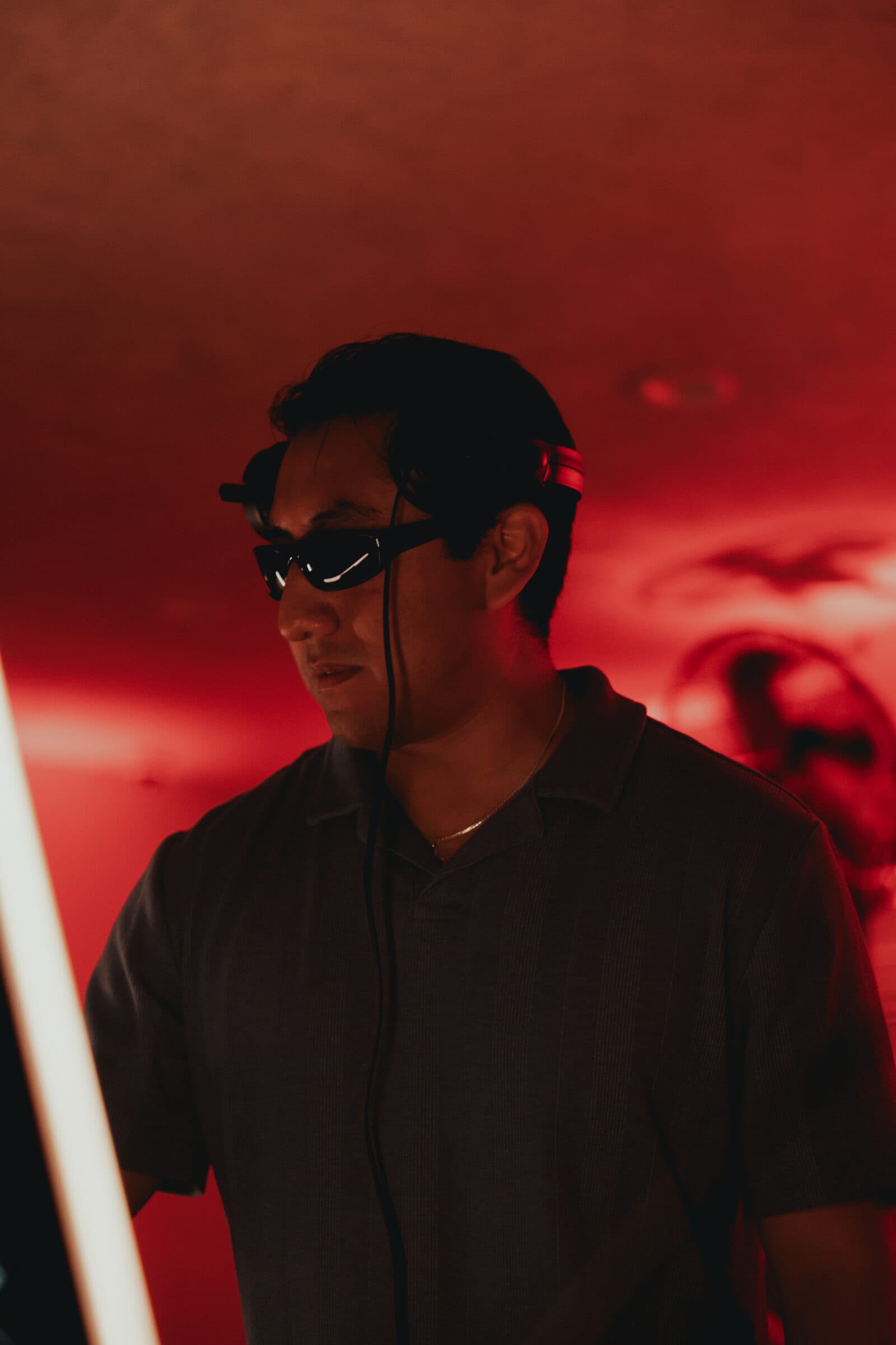 LP wearing sunglasses and headphones, lit in red at Mirage @ El Valle